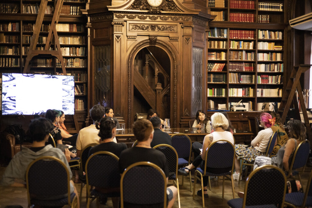 Presentación del Informe "Persistir y resurgir" en Buenos Aires, Argentina. Personas sentadas escuchan a oradoras en la Biblioteca Pública Esteban Echeverría.